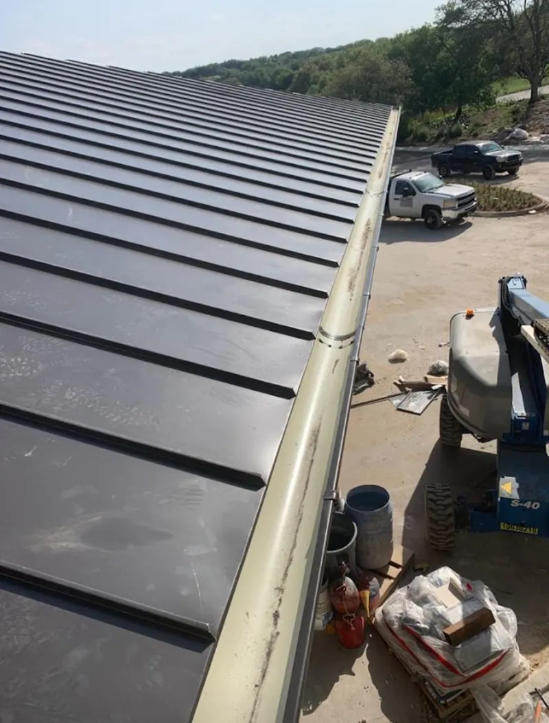 Standing seam panel and gutter detail on a metal roofing jobsite in Flint